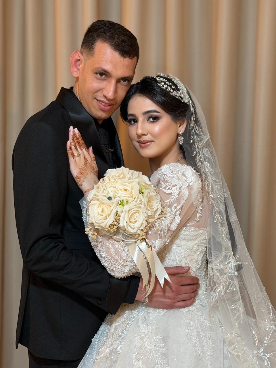 Couple de mariés enlacés, la mariée tenant son bouquet